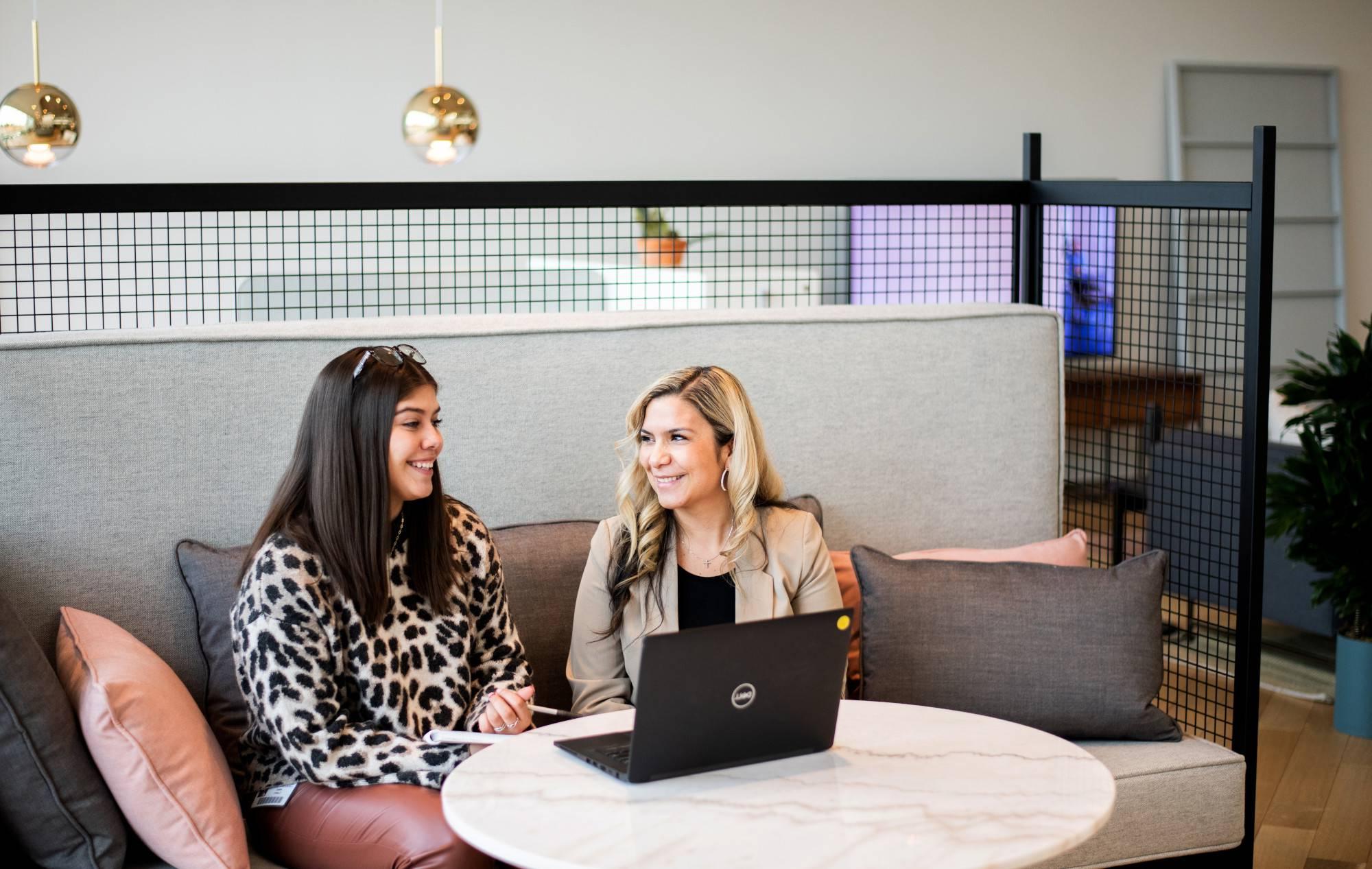 Two alums smile while working at a laptop at Steelcase
